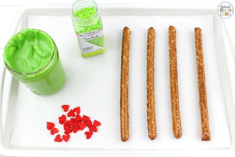 These delicious Grinch Chocolate Covered Pretzels will make everyone happy. They are so easy to make and Grinch Food Recipes look great on a party table. Add these Grinch Chocolate Covered Pretzels to your Grinch Food list and pull off a marvelous movie night or holiday party, Chocolate dipped pretzels, Grinch Party Ideas